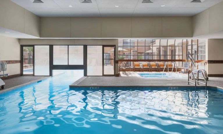 The hotel’s indoor pool has an adjacent hot tub and large windows, with a direct water link to the outdoor pool. 