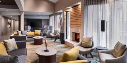 Sonesta Select Newport Middletown’s lobby lounge is furnished with comfy chairs and corners sofas, a fireplace and coffee tables, plus large windows.