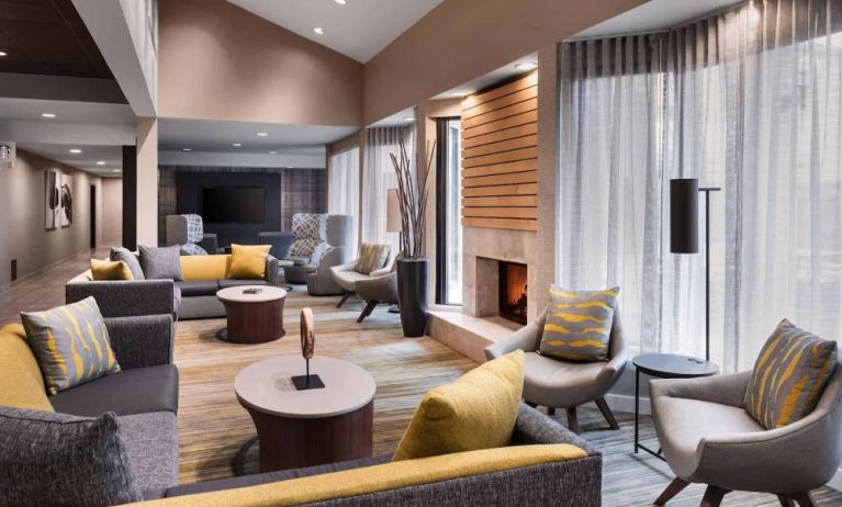 Sonesta Select Newport Middletown’s lobby lounge is furnished with comfy chairs and corners sofas, a fireplace and coffee tables, plus large windows.