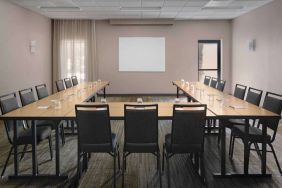 Meeting room in Sonesta Select Newport Middletown, with tables arranged in a U-shape facing a large whiteboard.