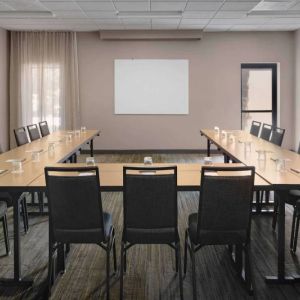 Meeting room in Sonesta Select Newport Middletown, with tables arranged in a U-shape facing a large whiteboard.