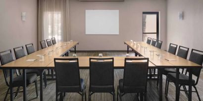 Meeting room in Sonesta Select Newport Middletown, with tables arranged in a U-shape facing a large whiteboard.