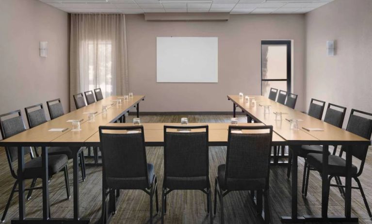 Meeting room in Sonesta Select Newport Middletown, with tables arranged in a U-shape facing a large whiteboard.