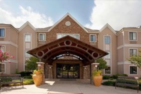 Sonesta ES Suites San Antonio Northwest - Medical Center’s exterior has pleasant greenery and benches, and a covered entranceway.