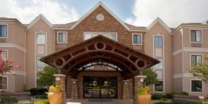 Sonesta ES Suites San Antonio Northwest - Medical Center’s exterior has pleasant greenery and benches, and a covered entranceway.