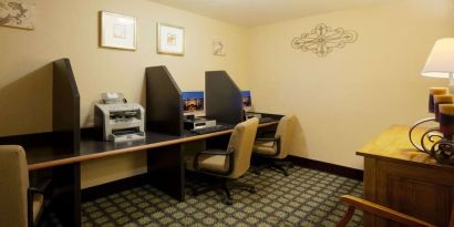 The hotel’s business center has multiple compute workstations, art on the wall, and a printer.