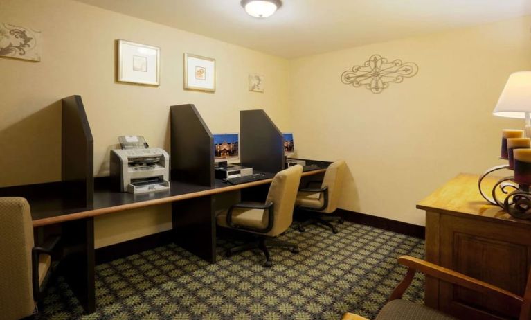 The hotel’s business center has multiple compute workstations, art on the wall, and a printer.