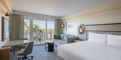 Double bed guest room in Royal Sonesta San Juan, featuring table, chairs, coffee table, and a sofa, plus balcony.