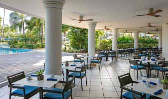 The hotel’s breakfast area has a hard floor, numerous ceiling fans, and small tables within easy reach of the pool.