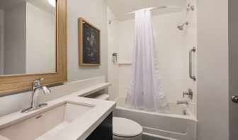 Guest bathroom in Sonesta Simply Suites Jersey City, furnished with bath and shower, lavatory, and sink and mirror.