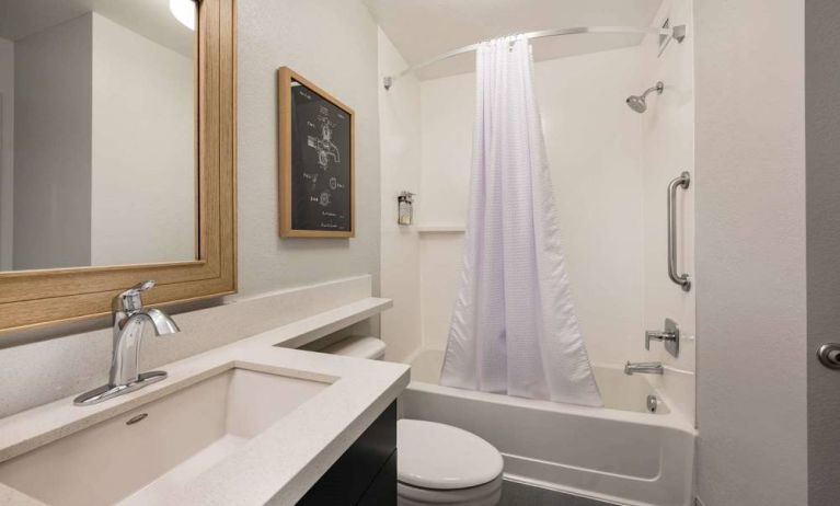 Guest bathroom in Sonesta Simply Suites Jersey City, furnished with bath and shower, lavatory, and sink and mirror.