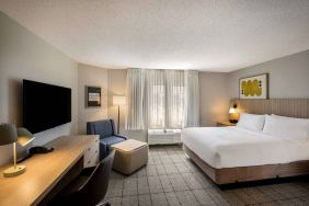 Sonesta Simply Suites Jersey City double bed guest room, featuring armchair, window, and widescreen television.