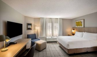 Sonesta Simply Suites Jersey City double bed guest room, featuring armchair, window, and widescreen television.