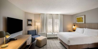 Sonesta Simply Suites Jersey City double bed guest room, featuring armchair, window, and widescreen television.