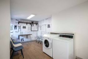 The hotel’s laundry room features a washer and drier, a pair of baskets, plus shelves and chairs.