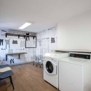 The hotel’s laundry room features a washer and drier, a pair of baskets, plus shelves and chairs.