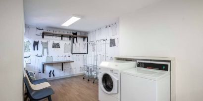 The hotel’s laundry room features a washer and drier, a pair of baskets, plus shelves and chairs.