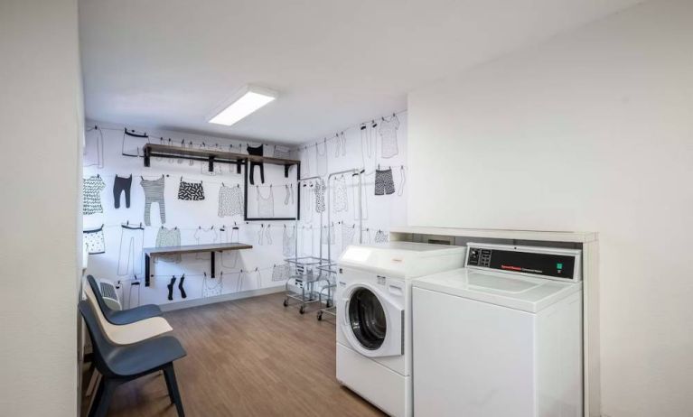 The hotel’s laundry room features a washer and drier, a pair of baskets, plus shelves and chairs.