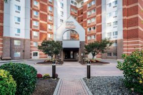 The hotel’s exterior has a brickwork surface, with flowers and trees either side of the entrance, which has the Sonesta Simply Suites name on it.