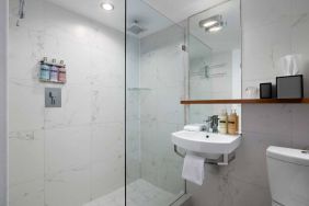 Guest bathroom in Nautilus by Sonesta, including shower, sink, mirror, and lavatory.