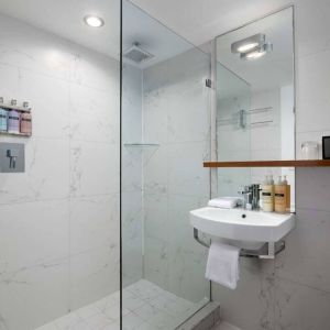 Guest bathroom in Nautilus by Sonesta, including shower, sink, mirror, and lavatory.