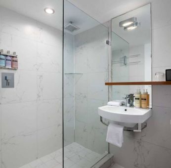 Guest bathroom in Nautilus by Sonesta, including shower, sink, mirror, and lavatory.