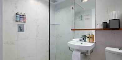 Guest bathroom in Nautilus by Sonesta, including shower, sink, mirror, and lavatory.