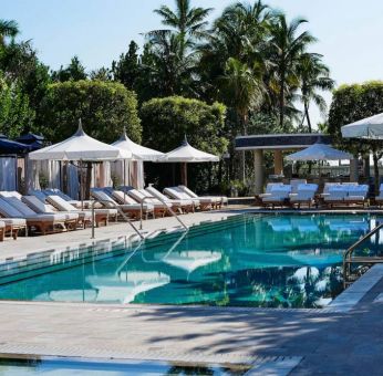 Nautilus by Sonesta’s outdoor pool has sun loungers (with shade available) by the side, and palm trees looming in the background.