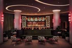 The lobby bar of Nautilus by Sonesta has a mix of traditional bar stool and more relaxed seating, numerous potted plants and subdued lighting.