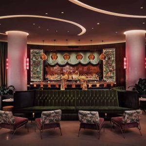 The lobby bar of Nautilus by Sonesta has a mix of traditional bar stool and more relaxed seating, numerous potted plants and subdued lighting.