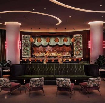 The lobby bar of Nautilus by Sonesta has a mix of traditional bar stool and more relaxed seating, numerous potted plants and subdued lighting.