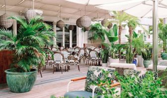 The hotel offers outdoor dining, with an abundance of plant life around the tables for four.