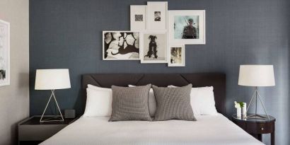 The Shelburne Sonesta New York double bed guest room, with art on the walls and bedside lamps.