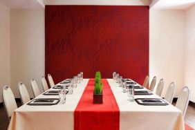 Meeting room in The Shelburne Sonesta New York, furnished with long table, 10 chairs around it, and a stark white and red color scheme.