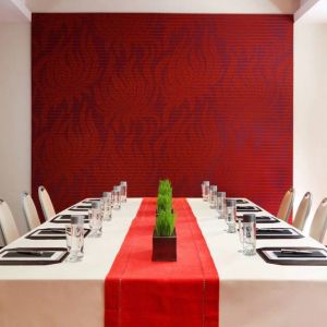 Meeting room in The Shelburne Sonesta New York, furnished with long table, 10 chairs around it, and a stark white and red color scheme.