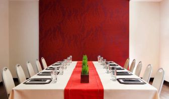 Meeting room in The Shelburne Sonesta New York, furnished with long table, 10 chairs around it, and a stark white and red color scheme.