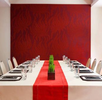 Meeting room in The Shelburne Sonesta New York, furnished with long table, 10 chairs around it, and a stark white and red color scheme.