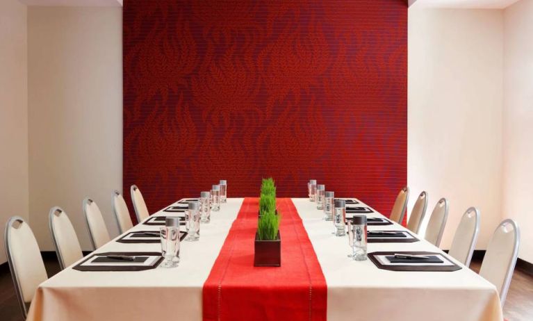 Meeting room in The Shelburne Sonesta New York, furnished with long table, 10 chairs around it, and a stark white and red color scheme.