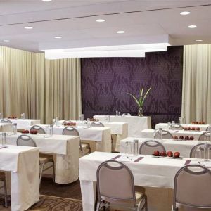 The Shelburne Sonesta New York meeting room with tables arranged in a classroom style facing a head table and space for over a dozen attendees.