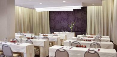 The Shelburne Sonesta New York meeting room with tables arranged in a classroom style facing a head table and space for over a dozen attendees.