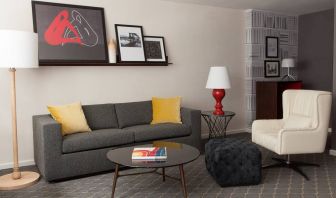 The Fifty Sonesta Select New York guest room living area, furnished with sofa, chair, coffee table, and artwork.