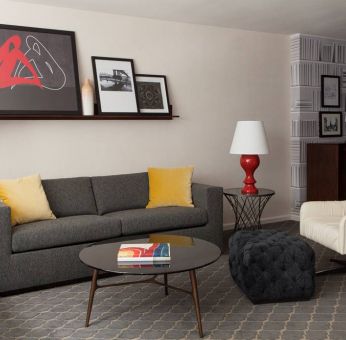 The Fifty Sonesta Select New York guest room living area, furnished with sofa, chair, coffee table, and artwork.