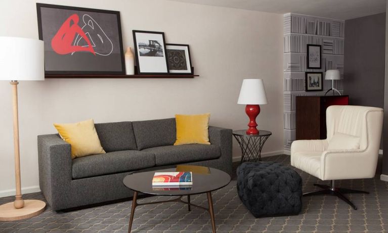 The Fifty Sonesta Select New York guest room living area, furnished with sofa, chair, coffee table, and artwork.