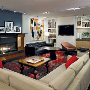 The Den’s lounge in The Fifty Sonesta Select New York features armchairs and sofas, coffee tables and a fireplace, plus a large TV.