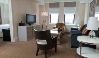 The Benjamin Royal Sonesta New York guest room, featuring chairs, sofa, coffee table, windows, and a television.