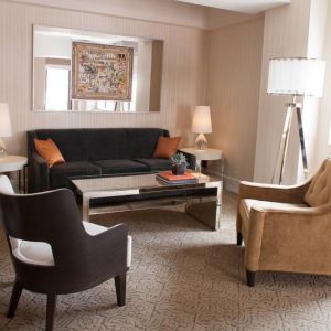 The Benjamin Royal Sonesta New York guest room living area, furnished with coffee table, chairs, TV, and sofa.