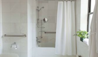 Guest bathroom in The Benjamin Royal Sonesta New York, featuring bath, shower, lavatory, and a small potted plant.