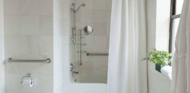 Guest bathroom in The Benjamin Royal Sonesta New York, featuring bath, shower, lavatory, and a small potted plant.