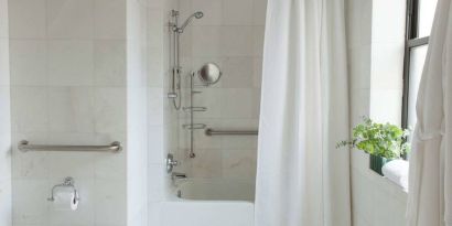 Guest bathroom in The Benjamin Royal Sonesta New York, featuring bath, shower, lavatory, and a small potted plant.