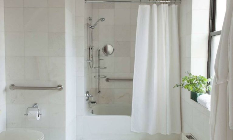 Guest bathroom in The Benjamin Royal Sonesta New York, featuring bath, shower, lavatory, and a small potted plant.